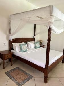 a bedroom with a canopy bed with white sheets and pillows at Rich Makuti in Watamu