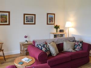 a living room with a purple couch and a table at Croft Cottage in Sharperton