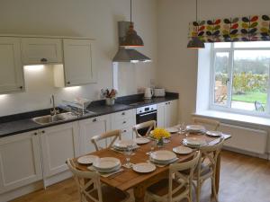 a kitchen with a wooden table with chairs around it at Croft Cottage in Sharperton