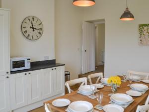 a dining room with a table and a clock on the wall at Croft Cottage in Sharperton
