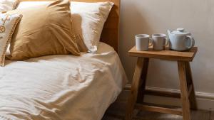 a bed with two mugs on a night stand next to a bed at The Nest in Stroud