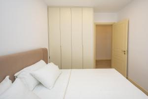 a bedroom with a bed with white sheets and pillows at Pomegranate House in Vlorë