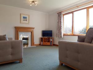 a living room with a couch and a television at Lismore Cottage in North Ballachulish