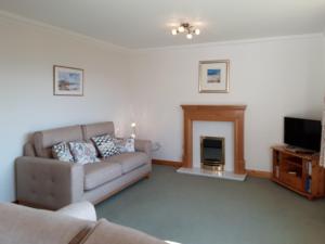 a living room with a couch and a fireplace at Lismore Cottage in North Ballachulish