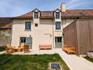 a house with two benches and a fence at Le Chêne Vert ,Gîte in Lureuil