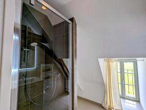 a shower with a glass door in a bathroom at Le Chêne Vert ,Gîte in Lureuil