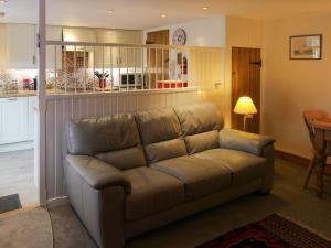 a brown couch in a living room with a table at Hollyhocks Cottage in Docking