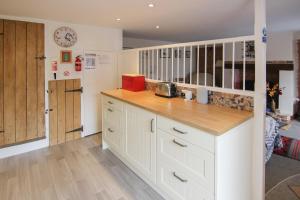 a kitchen with white cabinets and a wooden counter top at Hollyhocks Cottage in Docking +8 photos
