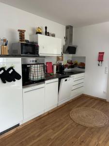 a kitchen with white appliances and a wooden floor at Charmantes Feriennest vor Seßlachs Stadtmauer im lebendigen Familienhaus in Seßlach