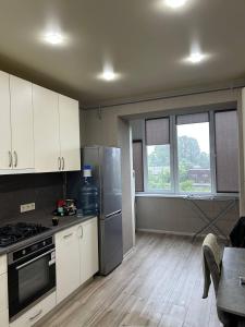 スームィにあるКвартира новострой Харьковскаяのキッチン(ステンレス製の電化製品、テーブル付)