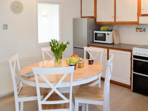 - une cuisine avec une table en bois et des chaises blanches dans l'établissement Cobi's Cape Cottage, à Saint Just