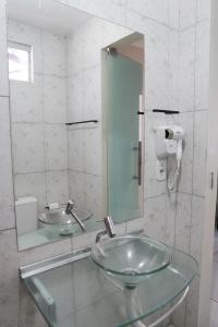 a bathroom with a glass sink and a mirror at Bendita Parada - Pousada in Sobral