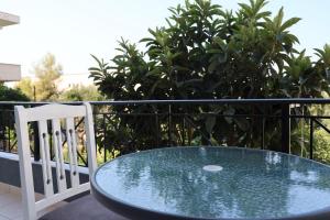 a glass table and a white chair on a balcony at A&K Apartments in Sarandë
