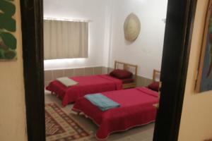 two beds in a room with red sheets at St.Jadoor Inn in Al Azraq ash Shamālī