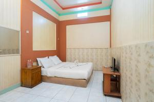 a bedroom with a bed and a tv in it at SAHABAT Hotel Tangerang By Reccoma in Kampungbaru +14 photos
