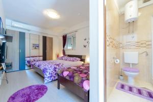 a bedroom with two beds and a bathroom with purple rugs at Apartments Milić in Mlini