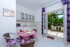 a kitchen with a table with a bowl of fruit on it at Apartments Milić in Mlini