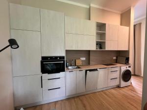 a kitchen with white cabinets and a washer and dryer at RUMIDO Station in Valmiera +9 photos