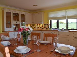 a kitchen with a wooden table with flowers and wine glasses at Lawford Lodge in Bonnybridge +20 photos