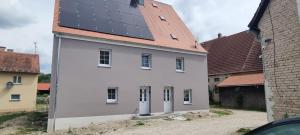 a white house with solar panels on its roof at gemütliche Ferienwohnung Achteltal in Simmelsdorf