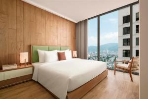 a bedroom with a white bed and a large window at Signature by M Village Beachfront Hotel in Da Nang +61 photos