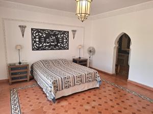 une chambre avec un lit et un lustre dans l'établissement Magnifique villa piscine Ghazoua, à Al Ghar 33 autres photos