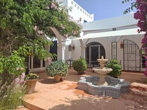 une cour avec une fontaine et quelques plantes dans l'établissement Magnifique villa piscine Ghazoua, à Al Ghar