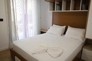 a bedroom with a white bed with a bow on it at A&K Apartments in Sarandë