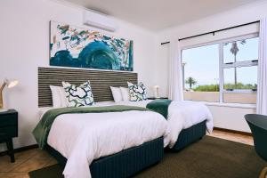 two beds in a bedroom with a window at Ocean House Swakopmund in Swakopmund