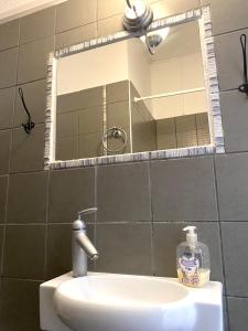 a bathroom sink with a mirror and a bottle of soap at Central Apart. 4U in Ierapetra +11 photos