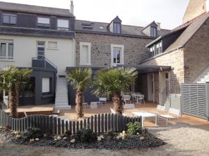 un patio con palmeras frente a una casa en Hotel Eden, en Saint-Malo