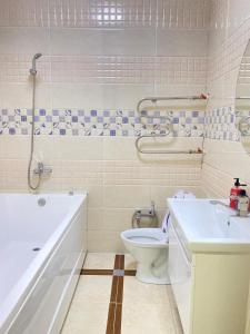 een badkamer met een bad, een toilet en een wastafel bij 2комн Барыс Арена in Astana