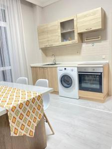 een keuken met een wasmachine en een wastafel bij 2комн Барыс Арена in Astana