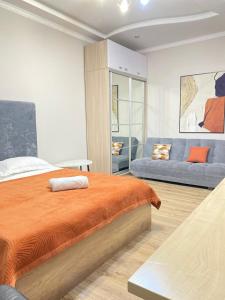 een slaapkamer met een bed en een bank bij 2комн Барыс Арена in Astana