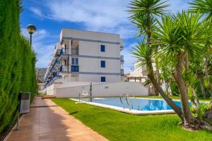 a swimming pool in front of a building with palm trees at Villablanca Vidaber in Oropesa del Mar