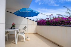 a table and a blue umbrella on a balcony at Villablanca Vidaber in Oropesa del Mar
