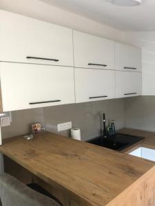 a kitchen with white cabinets and a wooden table at Ivanović smeštaj in Rose