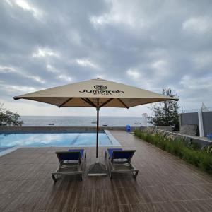 a large umbrella and two chairs next to a swimming pool at Jumeirah Palms Resort in Mombasa