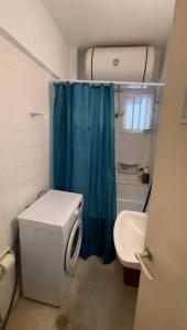a bathroom with a toilet and a blue shower curtain at Loutraki, Poseidonos seaside Apartments in Loutraki