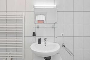 a white bathroom with a sink and a mirror at Charmante Altbau Wohnung Bregenz am See in Bregenz +19 photos