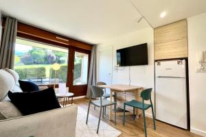 una cucina e un soggiorno con un tavolo e un frigorifero di Cosy 30m in the heart of Combloux a Combloux