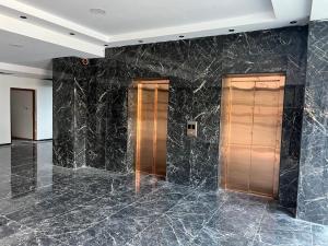 two elevators in a lobby with black marble walls at Grand Lake View Apartment in Ohrid
