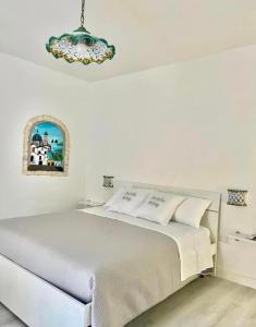 Habitación blanca con cama y lámpara de araña. en B&B Due Su Due Holiday, en Vietri