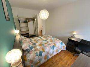 een slaapkamer met een bed, een bureau en 2 verlichting bij Logement Neuf Cosy avec Espaces Communs Premium 13 in Belfort