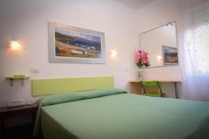 a bedroom with a green bed and a painting on the wall at Hotel Villa Denia in San Vincenzo