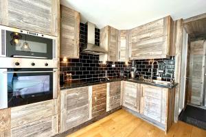 Una cocina con gabinetes de madera y un horno de estufa. en Le Repère de l'Ours, en Megève