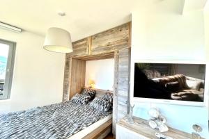 1 dormitorio con pared de madera, cama y TV en Le Repère de l'Ours, en Megève