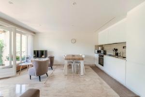 a kitchen with white cabinets and a table and chairs at Morcote Romance by Quokka 360 - flat with patio and communal pool in Morcote