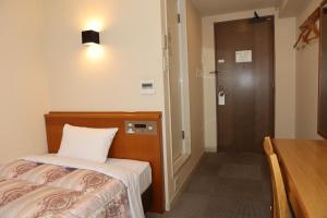 um quarto de hotel com uma cama e uma porta com uma porta em アイリスイン知立 em Chiryu