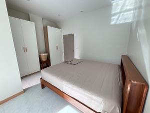 a small bedroom with a bed and white walls at Bay Sand Villa by Jai House Phuket in Ban Klang